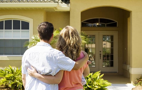 A man and a woman looking at the entrance of their yellow house